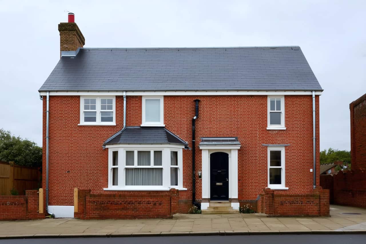 The same roof after a full re-roof: new grey slate-effect tiles, a straight ridge line and fresh lead flashing around the chimney