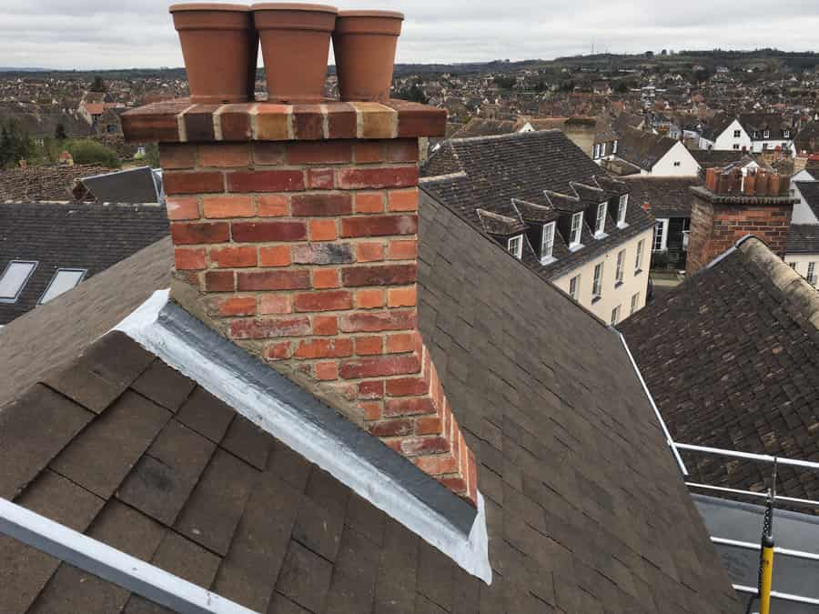 Rebuilt Victorian chimney stack with fresh brickwork and new stepped lead flashing, seen from roof level in Market Harborough